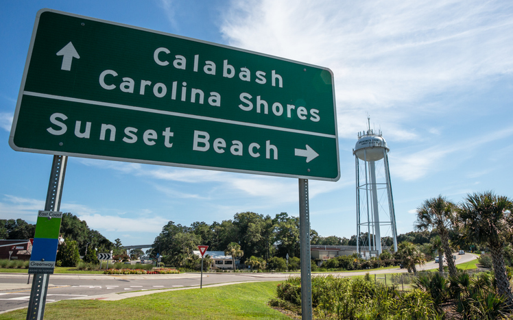 A road sign in coastal North Carolina directs visitors to Calabash, Carolina Shores, or Sunset Beach.